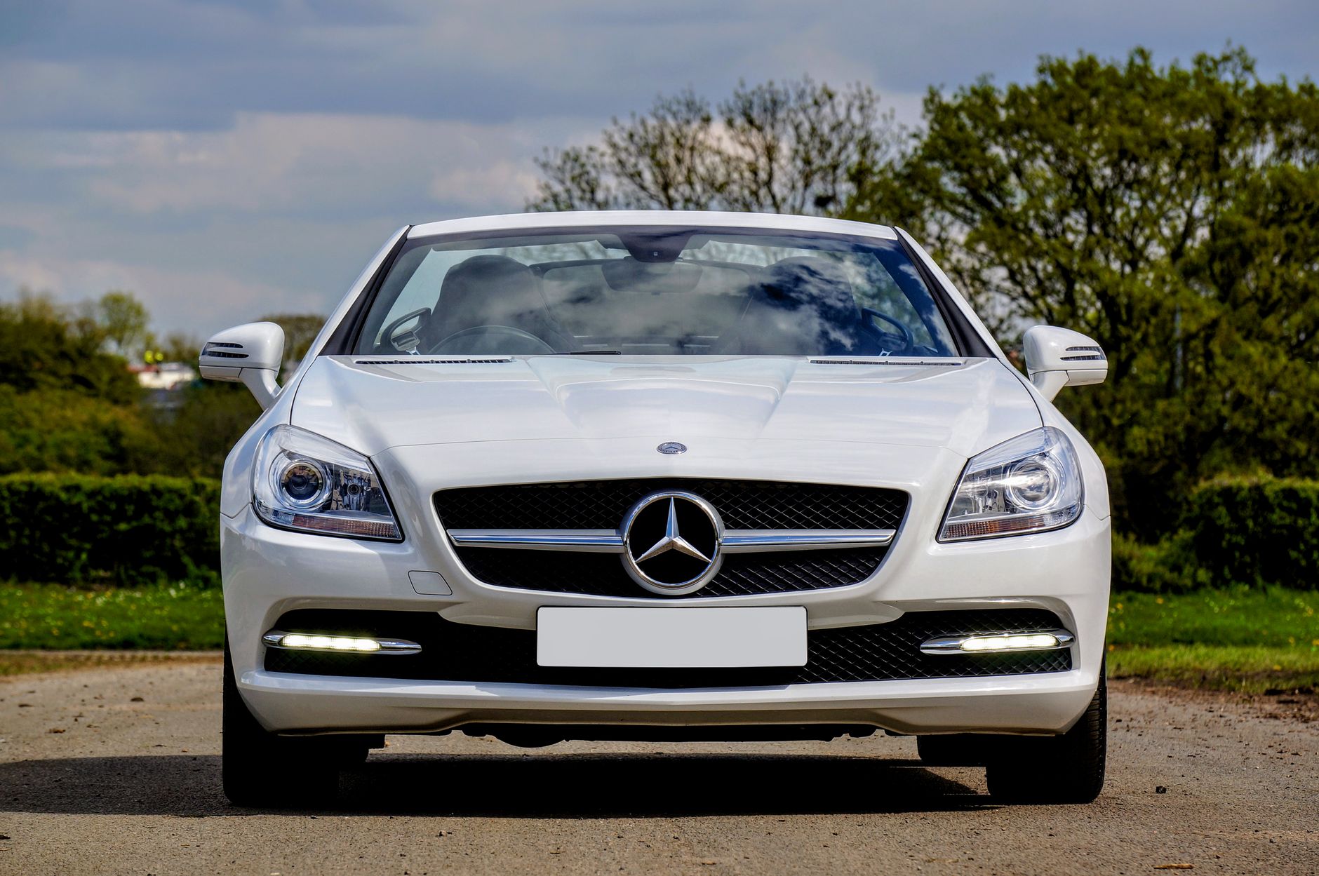 Front view of a white Mercedes-Benz SLK 250 convertible parked in a scenic outdoor setting.