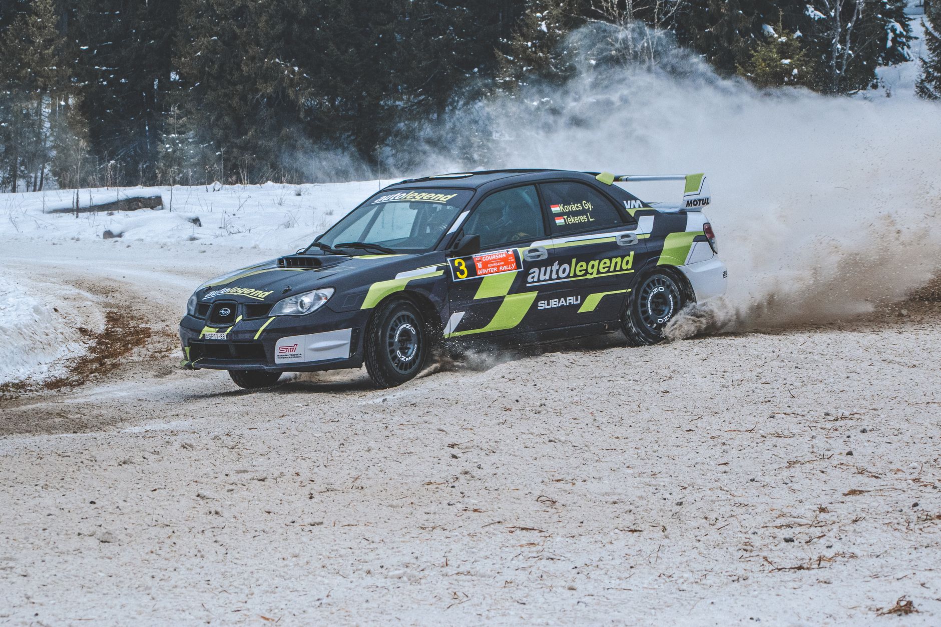 Subaru Impreza rally car drifting on a snowy forest track in Comandău, Romania.