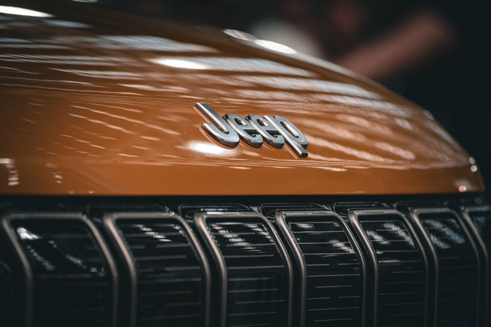Detailed view of a Jeep brand logo on a car grille, showcasing automotive design.