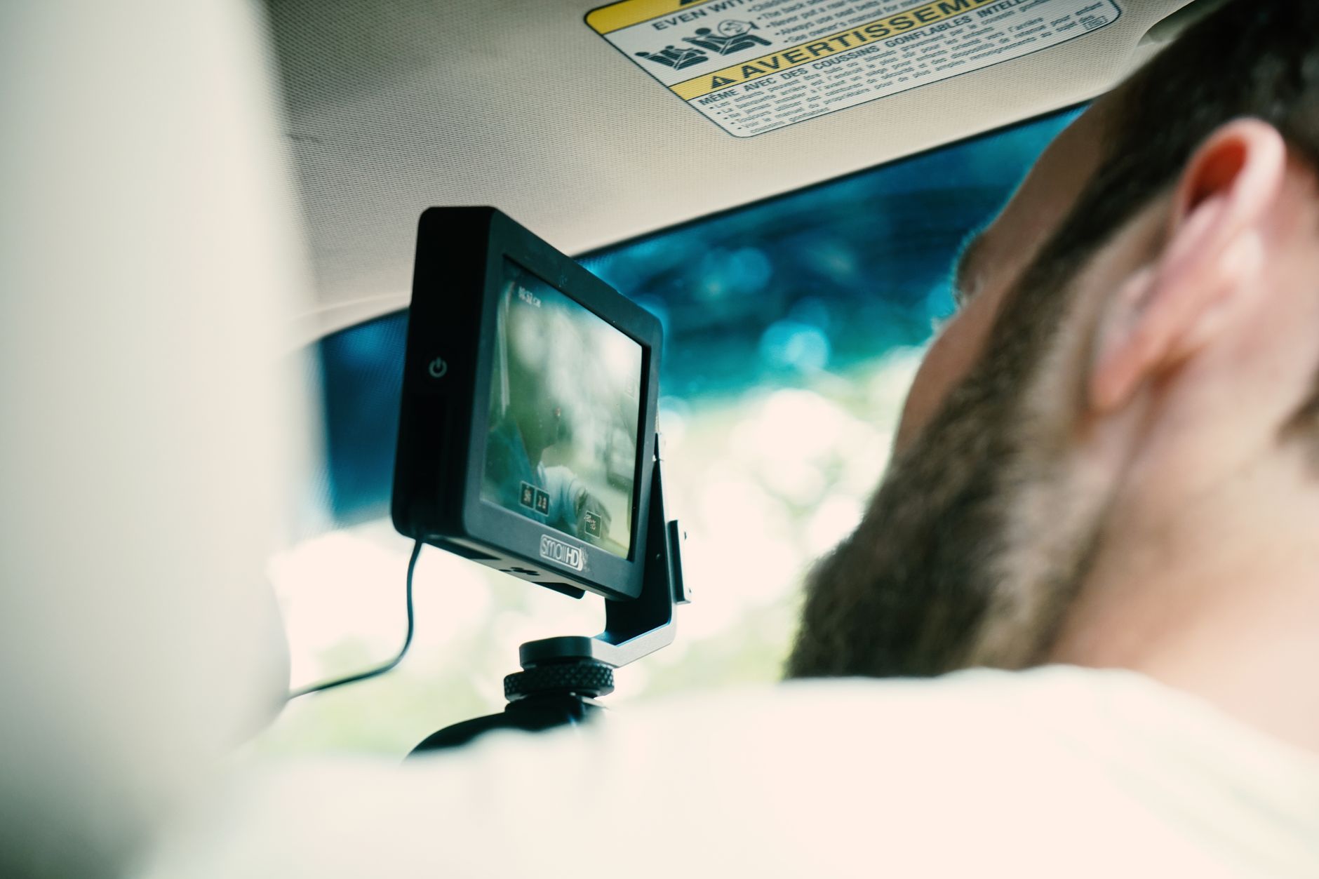 Adult male using dashboard camera while driving. Focus on modern technology and screen.