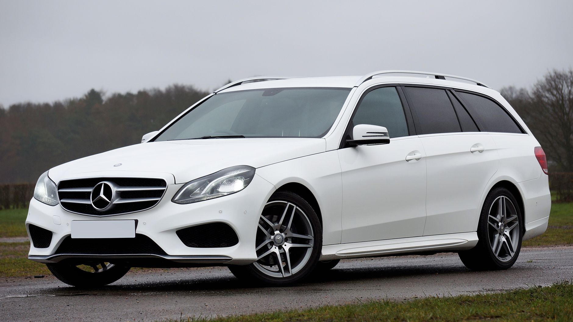 A sleek white Mercedes E-Class wagon parked outdoors under a cloudy sky, showcasing elegance and performance.