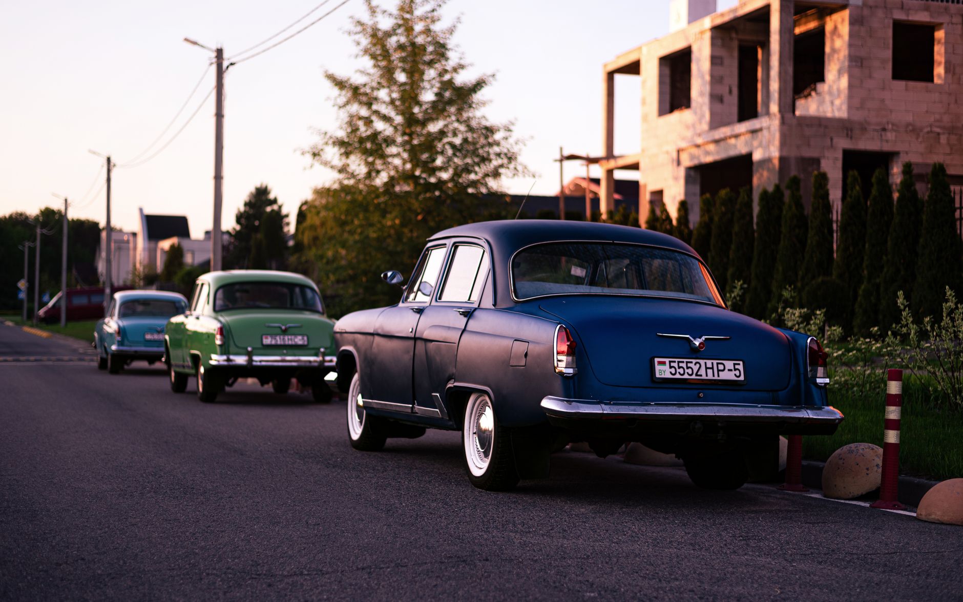 Classic cars parked alongside a quiet urban street during sunset, capturing a nostalgic vibe.