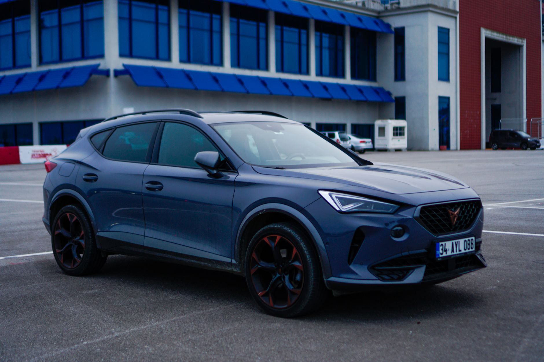 A blue SUV parked outside a modern office building with blue accents, highlighting urban style.