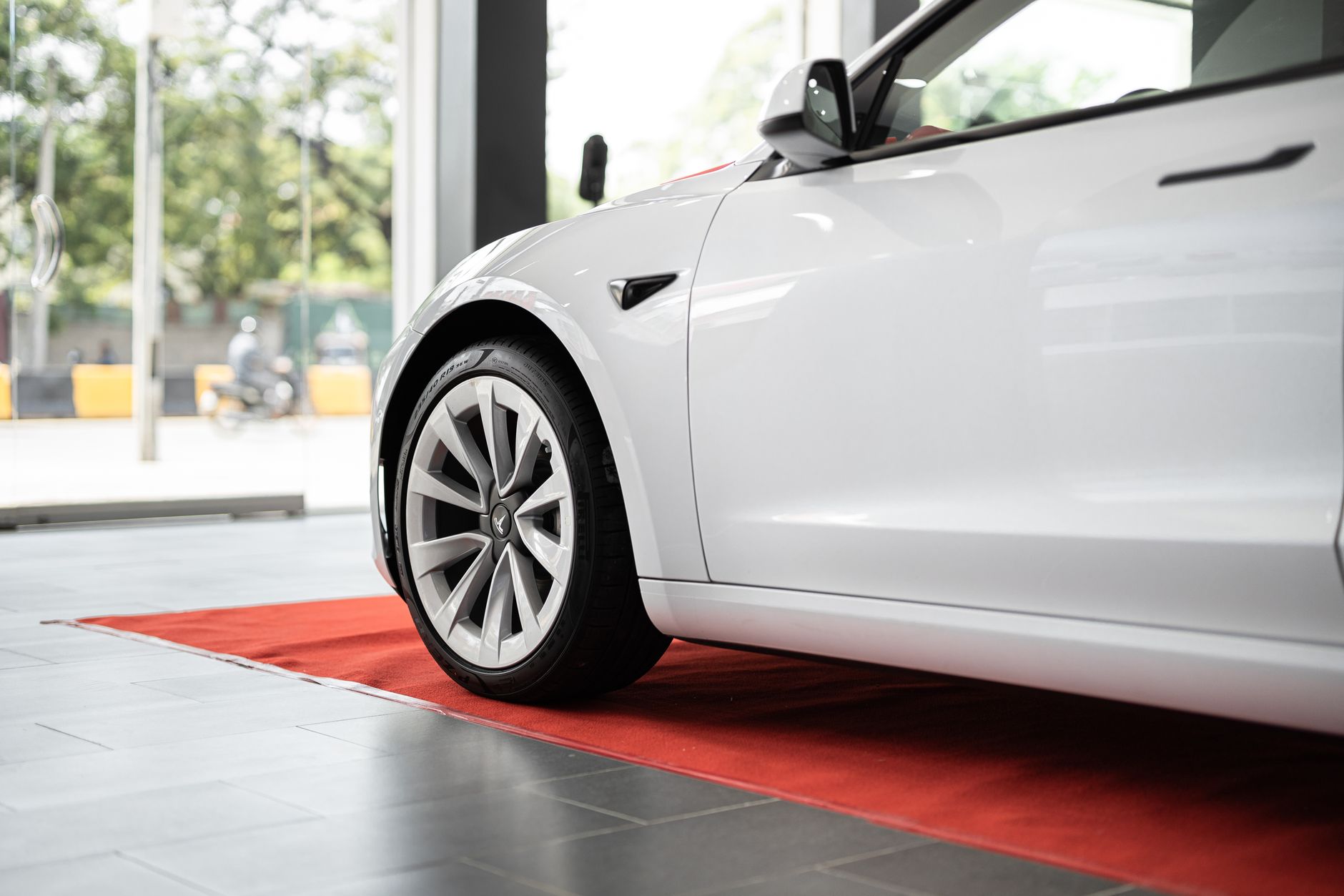 Sleek white electric car on display in a modern showroom on a red carpet.