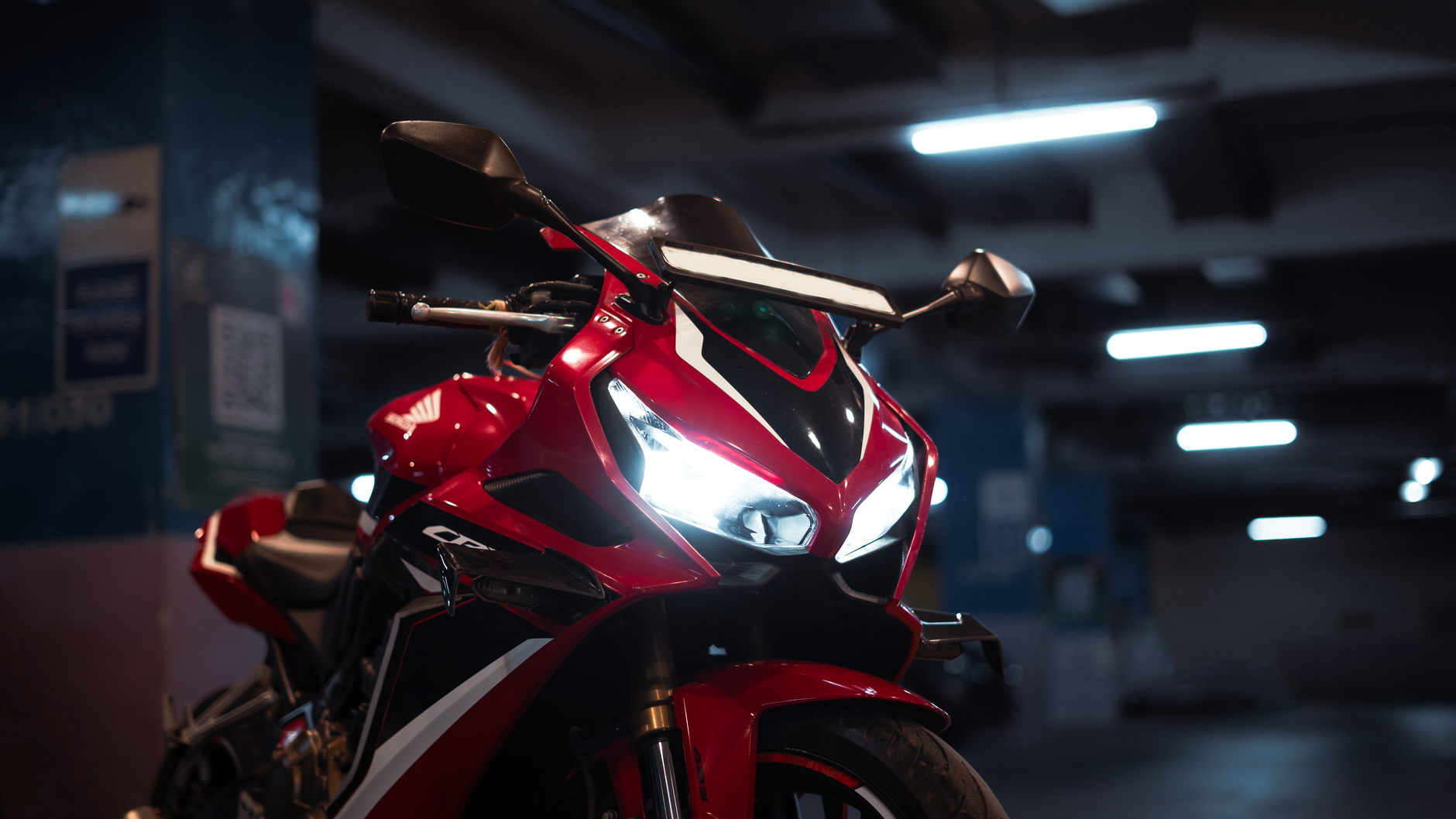 High-performance red sports motorcycle parked indoors with headlights on.