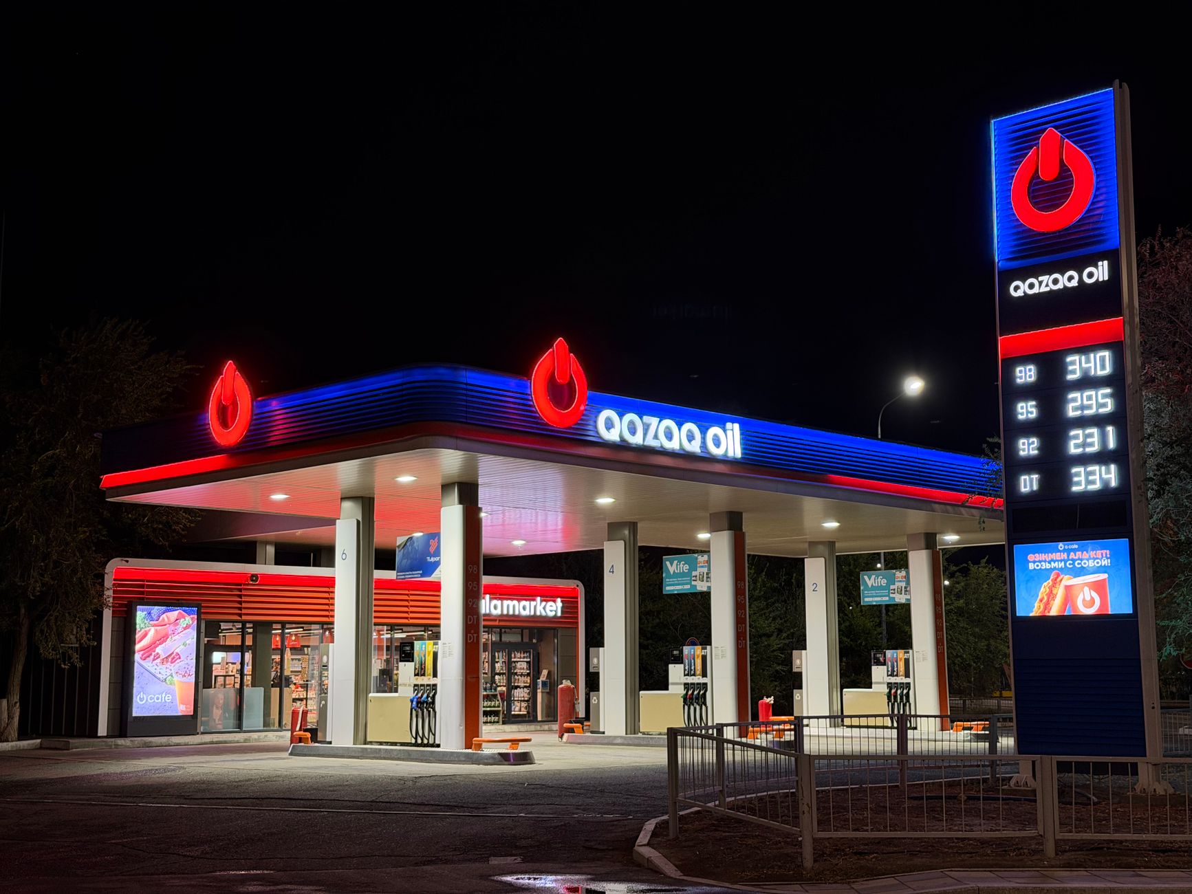 A brightly lit gas station at night featuring bold signage and illuminated fuel price display.