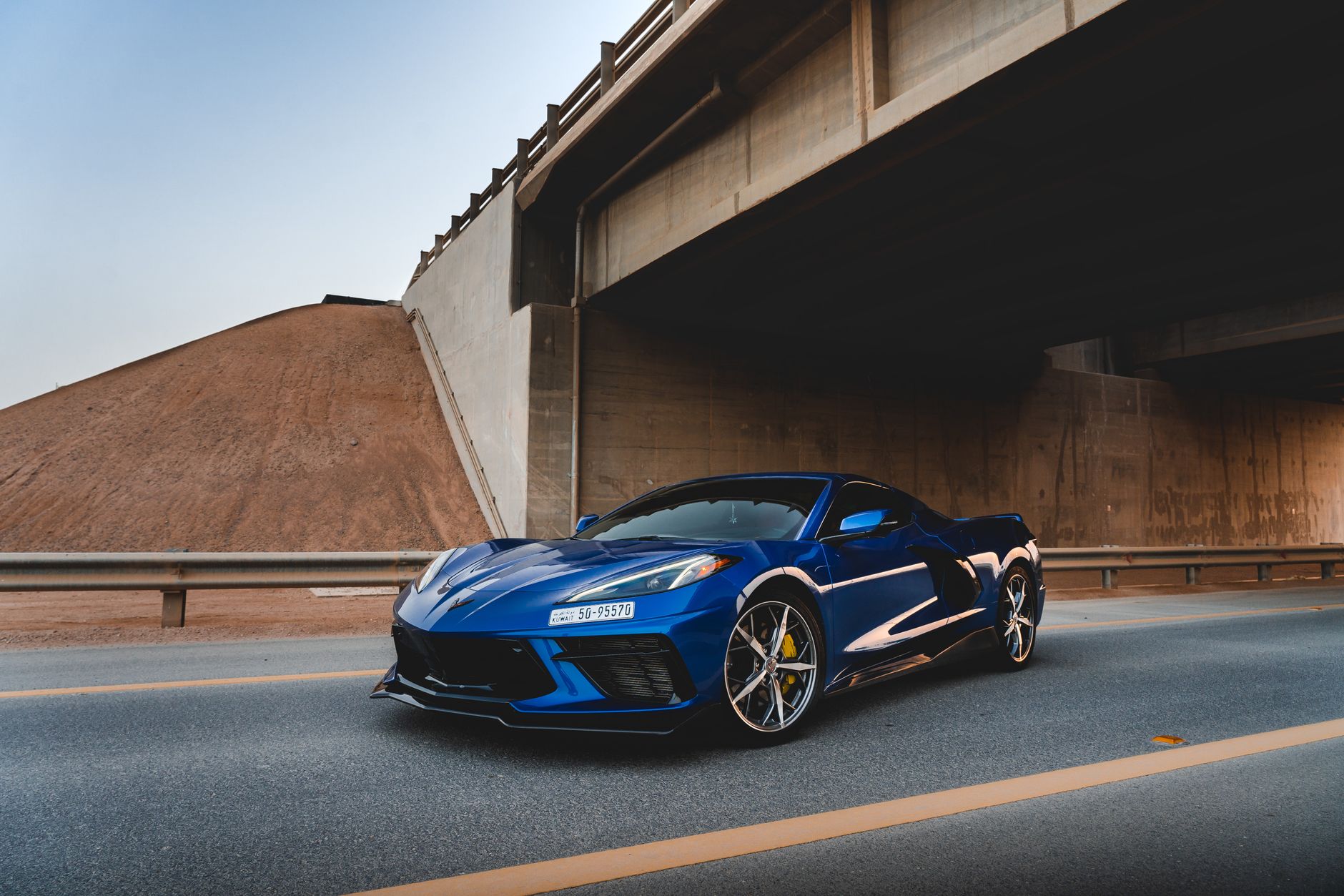 A luxury blue sports car parked under an urban bridge capturing modern elegance.