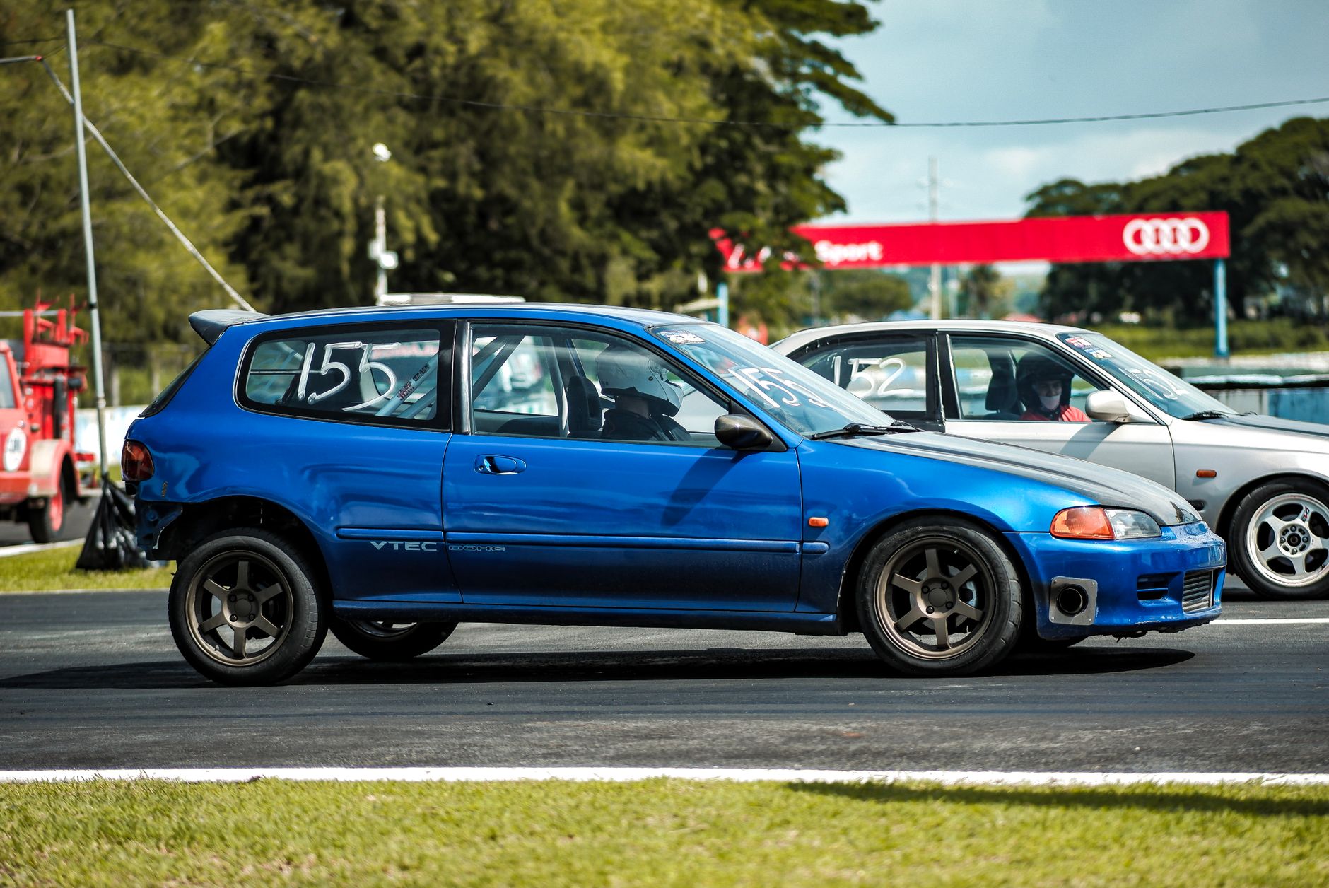 Bright blue car racing on track during a sunny day, capturing action and excitement.