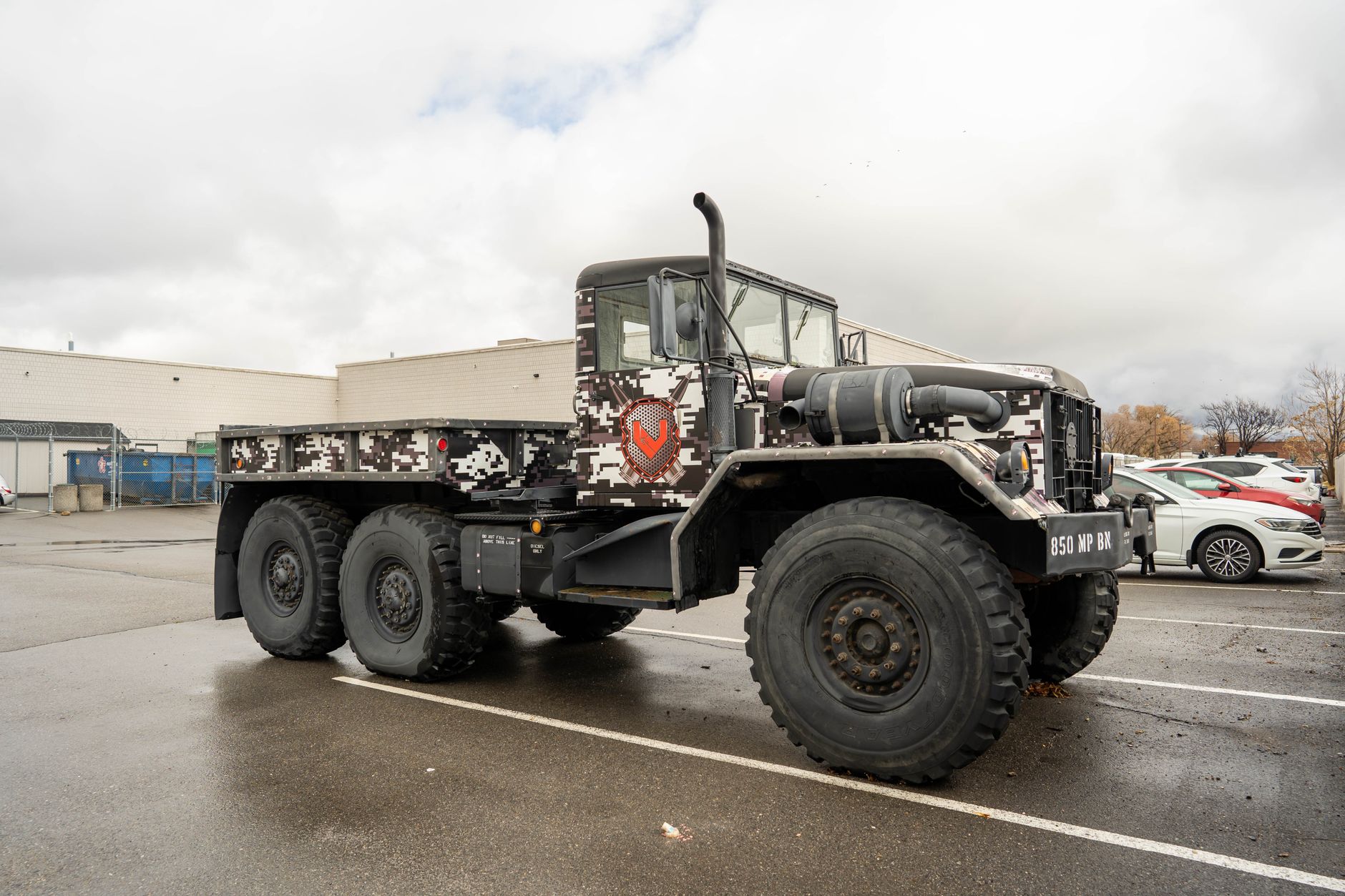 Large military truck with urban camo parked, showcasing power and rugged design.