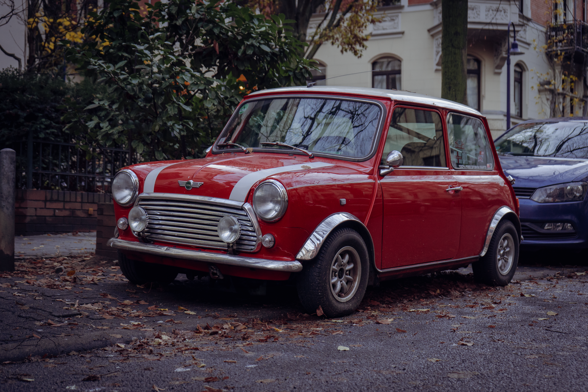 Classic red Mini Cooper parked on a leafy autumn street in Wiesbaden, Germany.