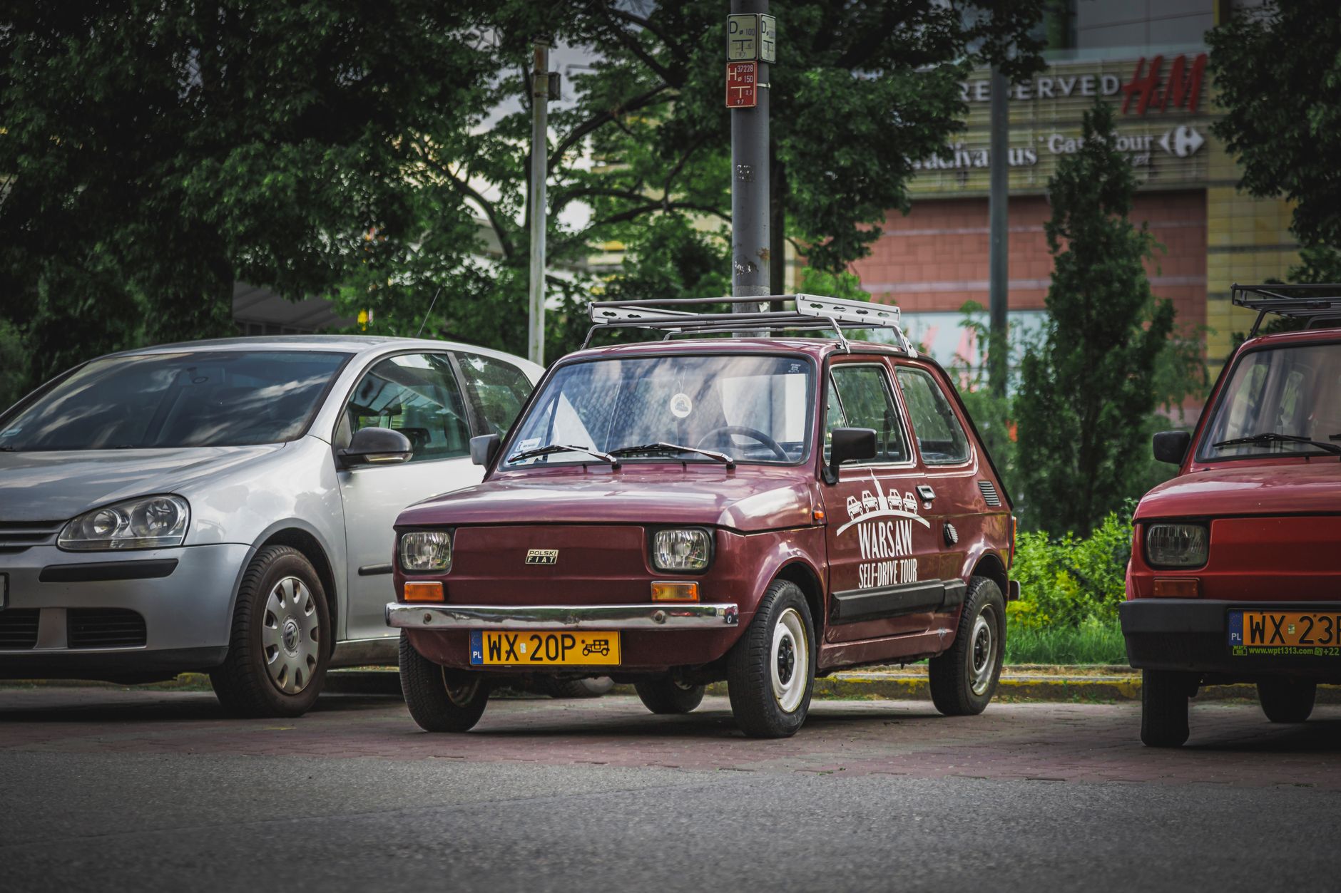A vintage Polish car parked on a Warsaw street, showcasing city life and classic automotive design.