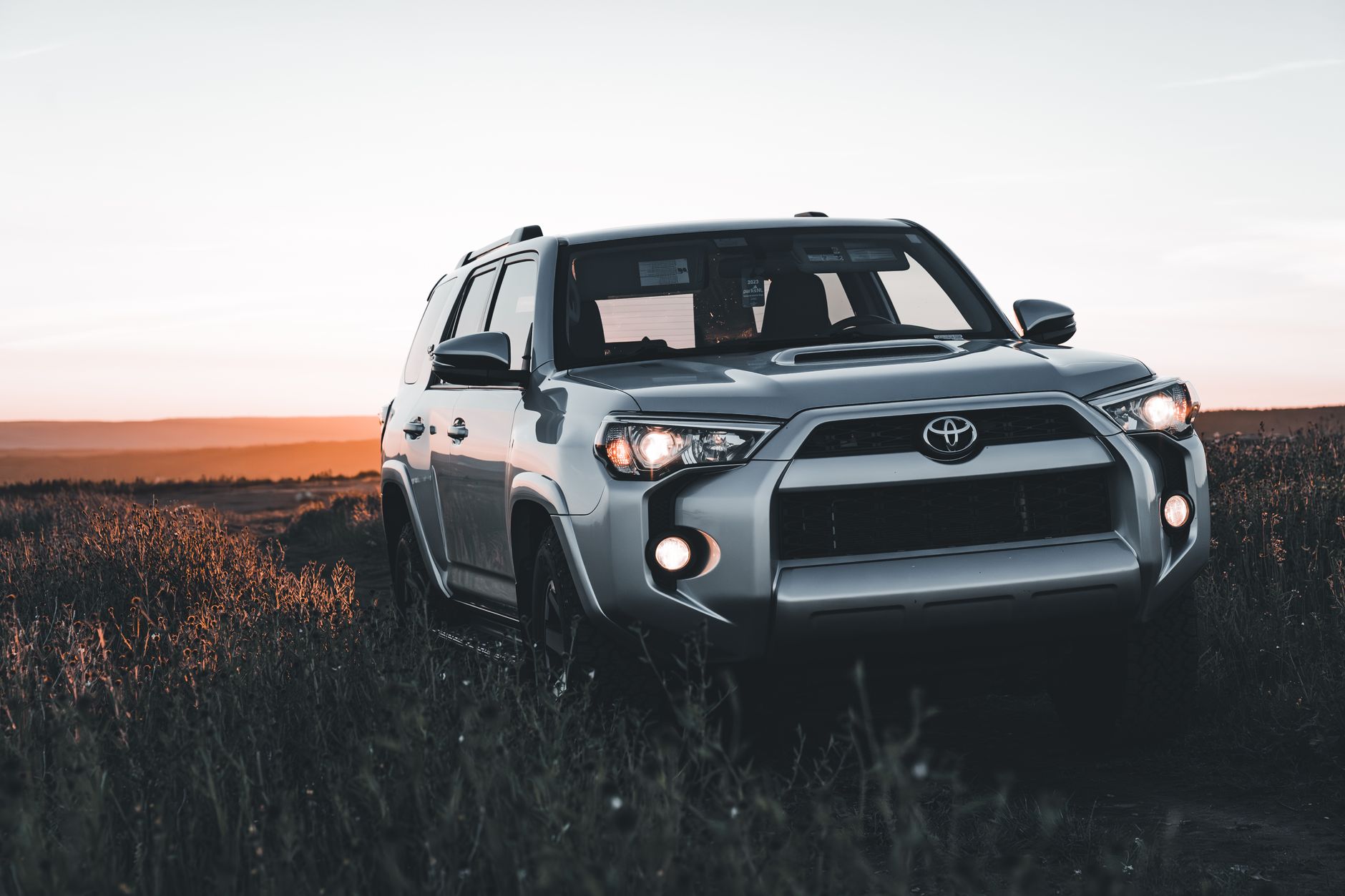 Silver Toyota SUV parked off-road during sunset, showcasing rugged scenery and adventure vibes.