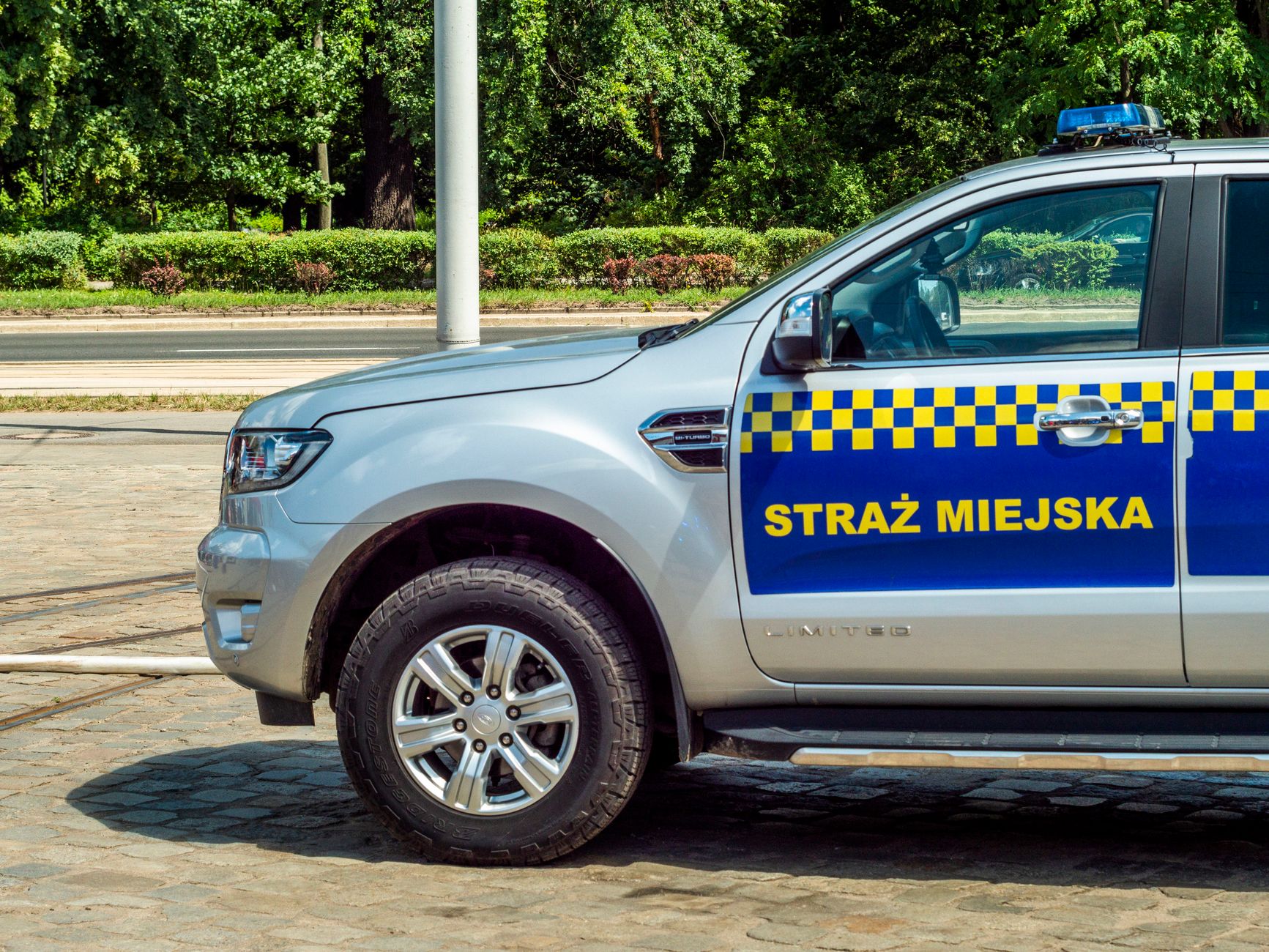 A municipal police vehicle parked on a cobblestone street during the day.