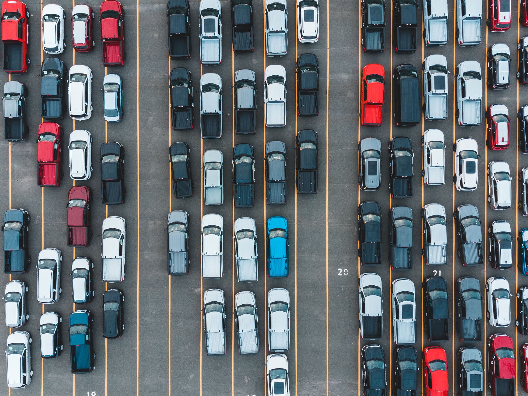 Aerial shot of parked cars in rows viewed from above, showcasing transportation and organization.