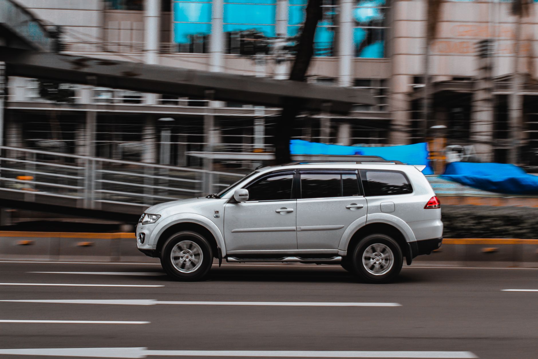 Silver SUV in motion on an urban road with a blurred background for a dynamic effect.