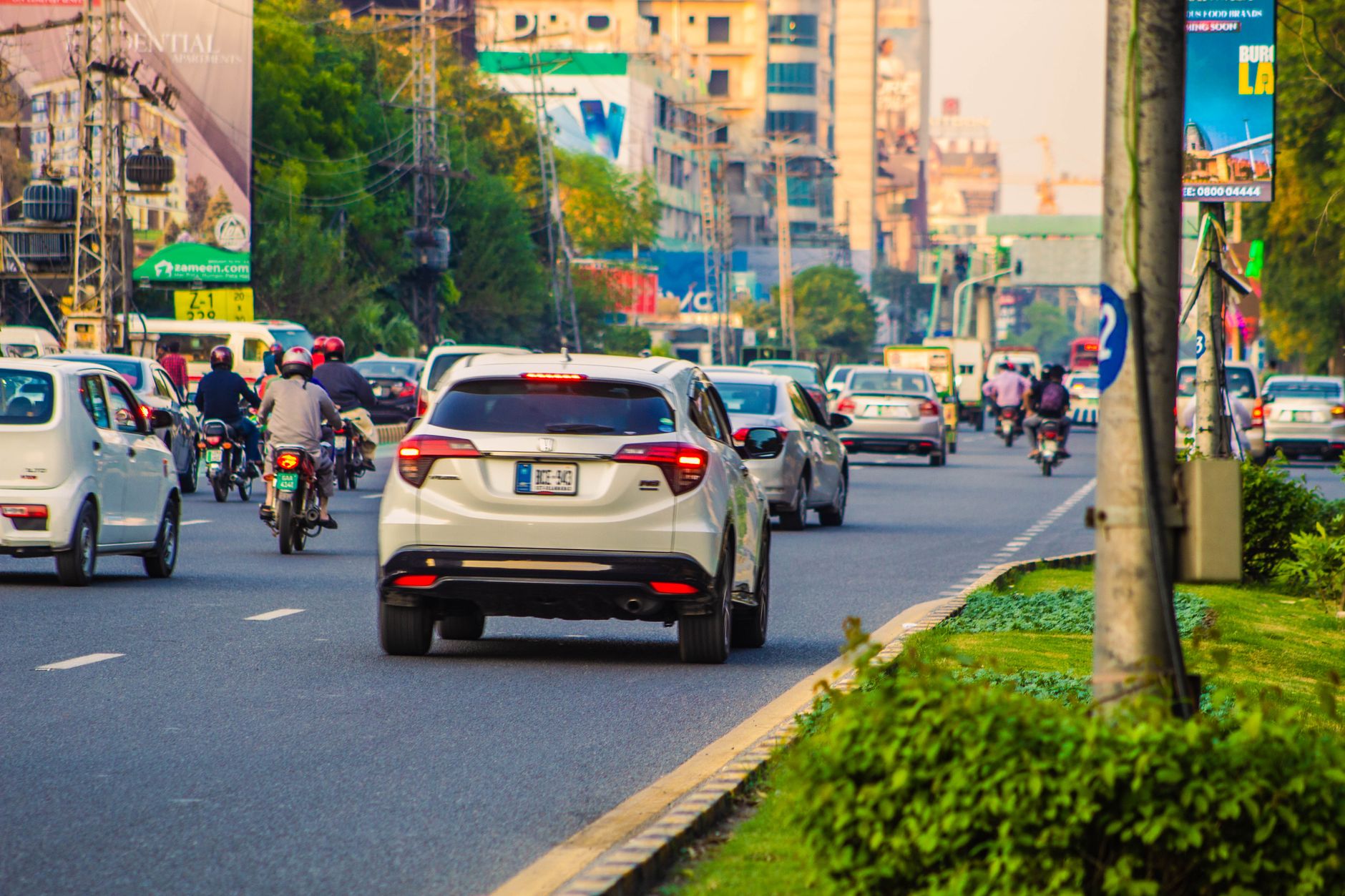 Urban street scene in Punjab, Pakistan, bustling with traffic including cars and motorcycles.