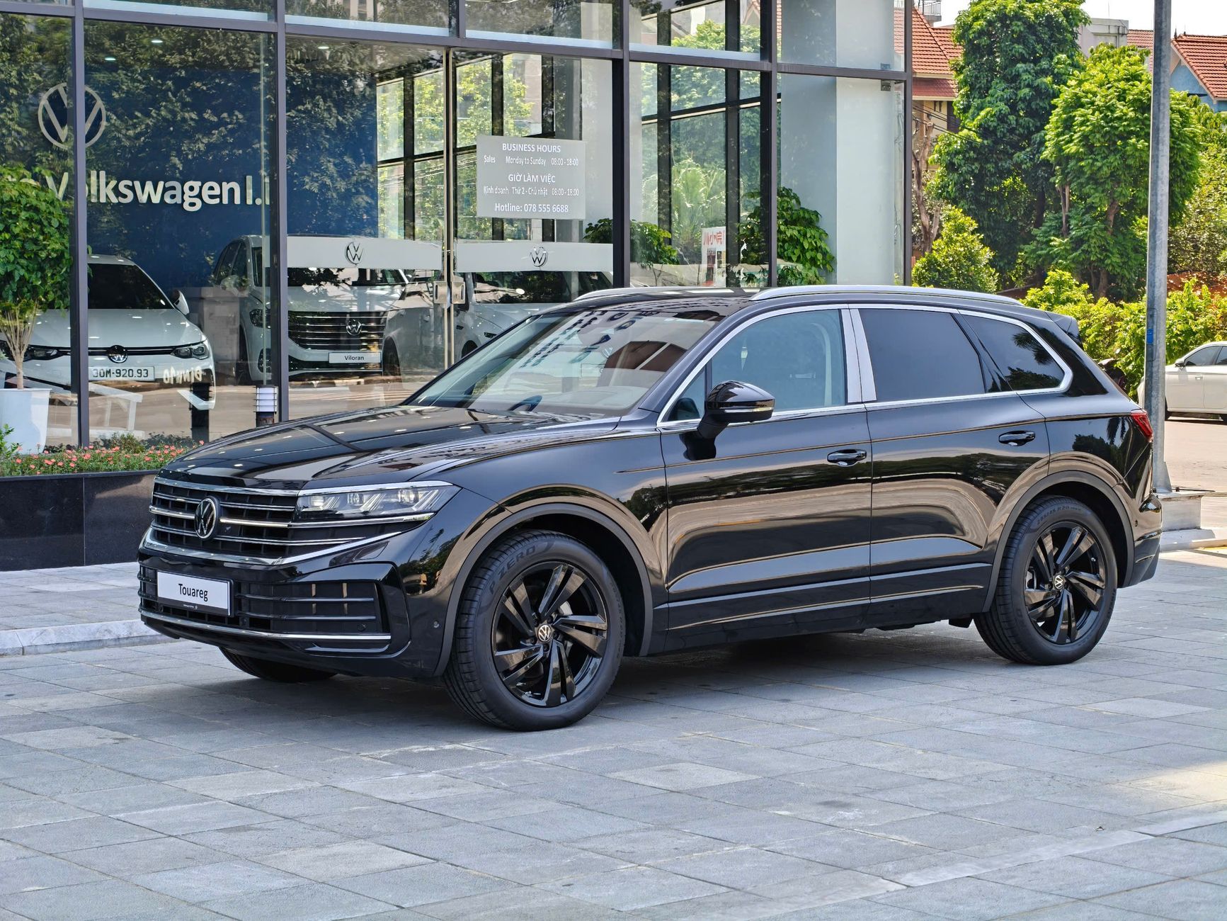 A modern black SUV showcased at a Volkswagen dealership on a sunny day.